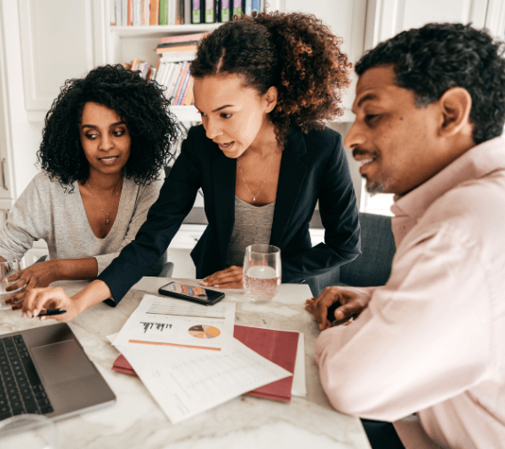 two female and one male employee discussing work via laptop on a table