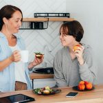 care giver talking with young person who appears happy in the kitchen